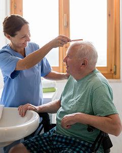 Elderly man having his hair brushed by carer