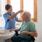 Elderly man having his hair brushed by carer
