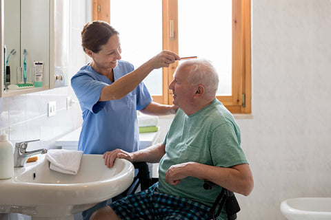 Elderly man having his hair brushed by carer