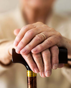 lady with her hands on walking stick senior living aids