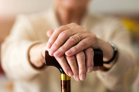 lady with her hands on walking stick senior living aids