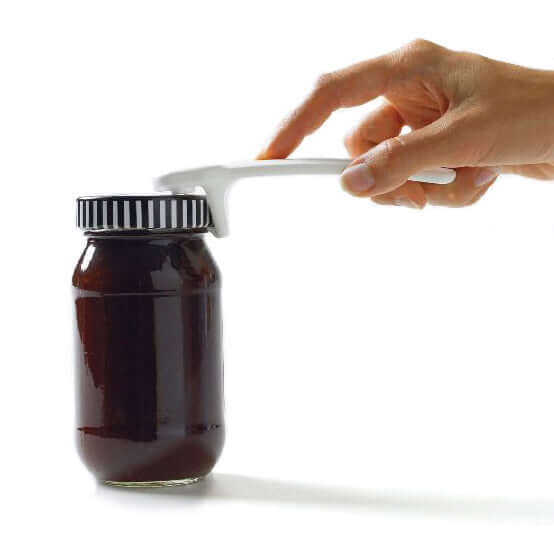 Hand using Maxi Jar Key to easily open a jar with a tall lid, showcasing its simplicity and ergonomic design.