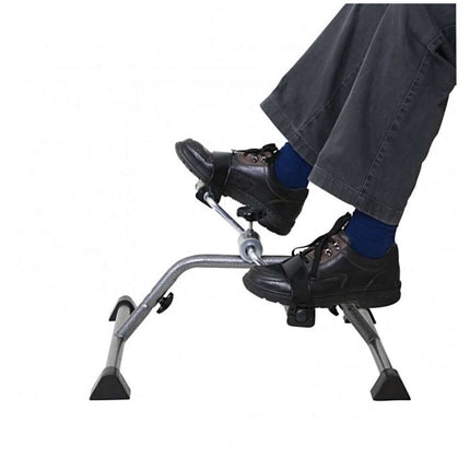 Close-up of feet using a pedal exerciser, showcasing its compact design and non-slip features for effective exercise.