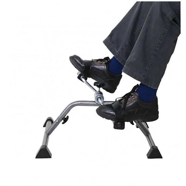 Close-up of feet using a pedal exerciser, showcasing its compact design and non-slip features for effective exercise.