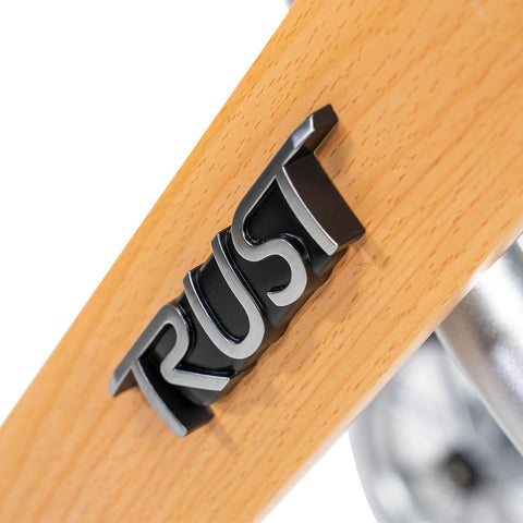 Close-up of the 'RUST' logo on a beech wood rollator frame, highlighting quality craftsmanship and design.