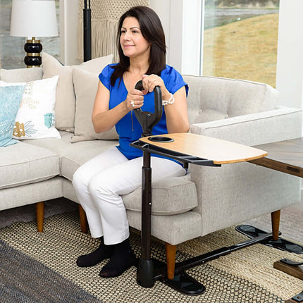 Woman using Stander Assist-A-Tray safety handle and swivel tray for support while seated on a couch.