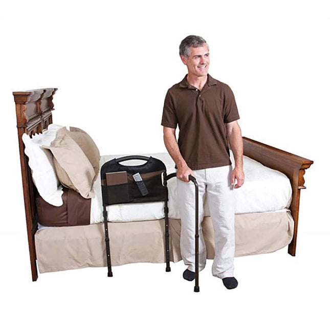 Man standing next to Stander Mobility Bed Rail, providing stability and support for getting in and out of bed.